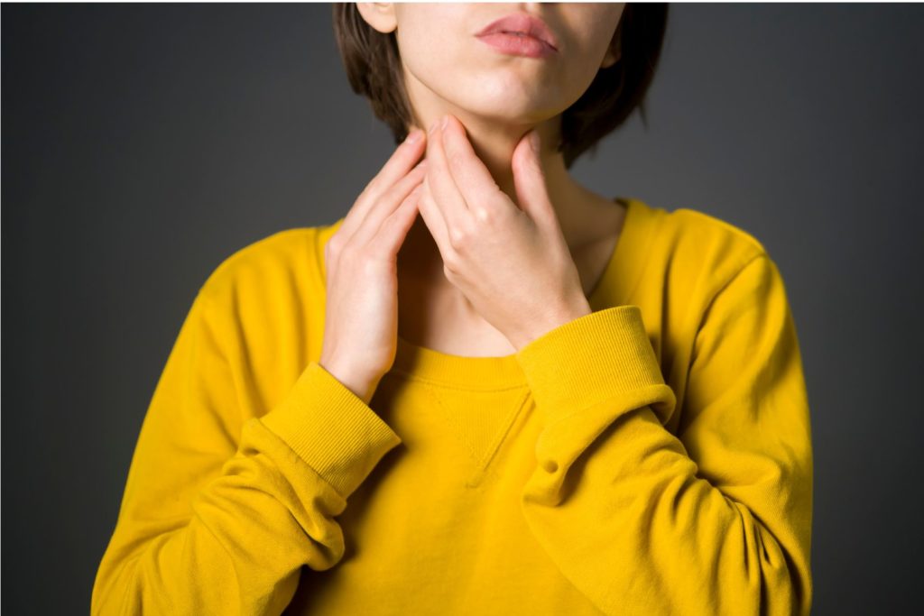 Image of Woman feeling her throat for "Everything You Need To Know About Your Thyroid" Blog Post