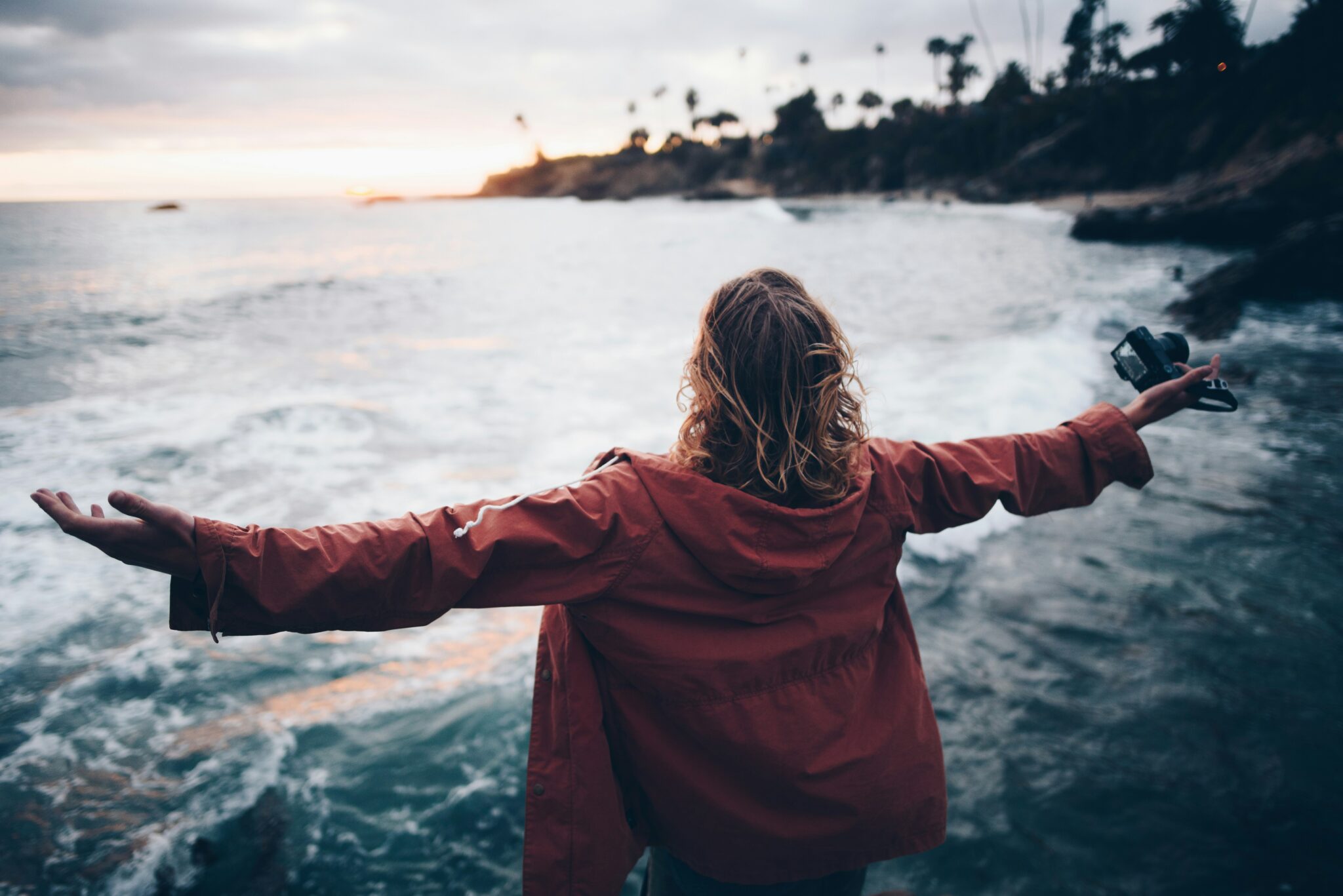 Woman with arms open facing the ocean, a picture of surrender through fear and anxiety