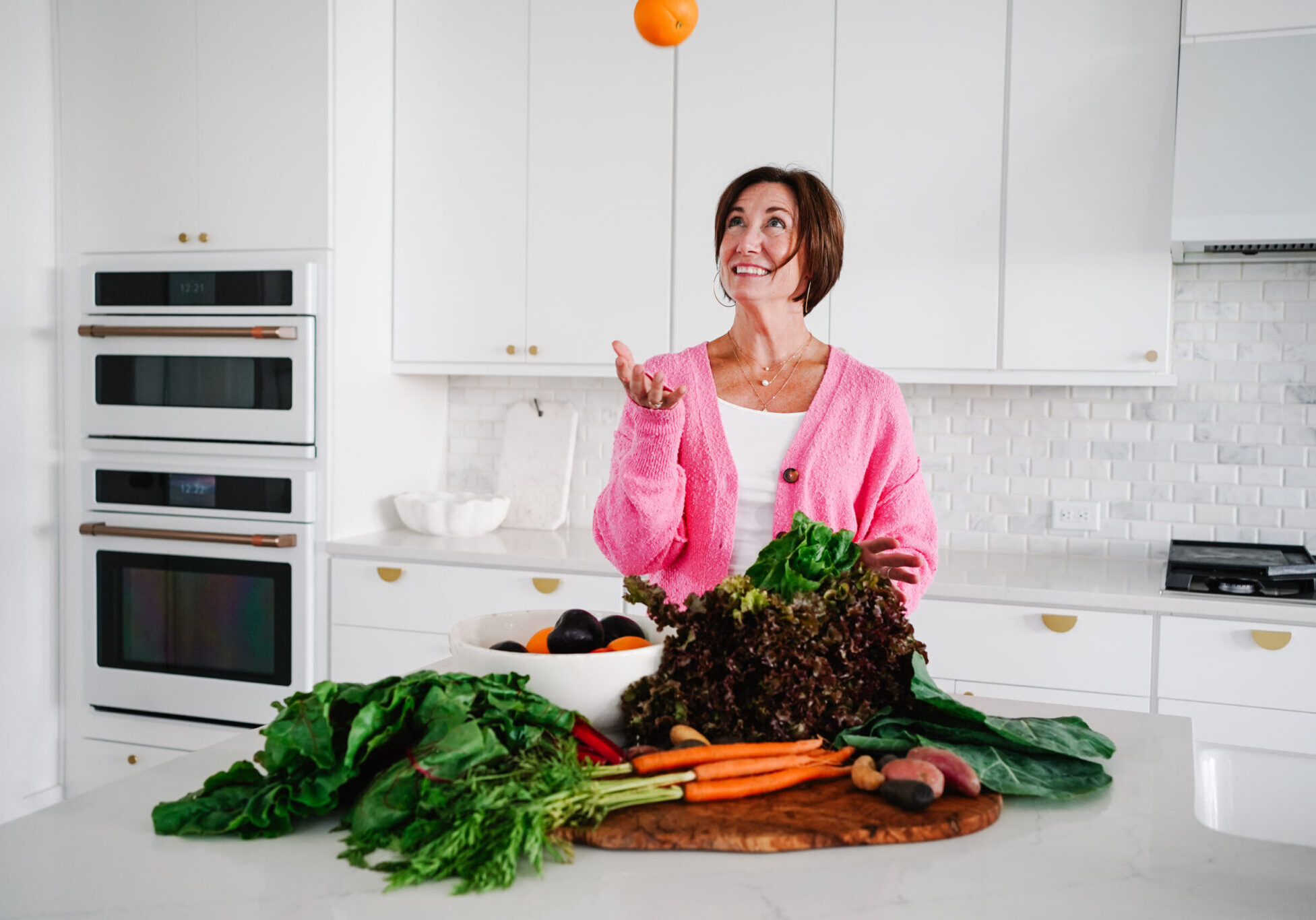 Woman cooking with fresh veggies and fruit.